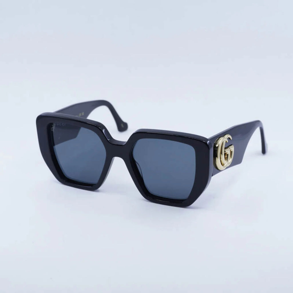 Black sunglasses with a gold logo on a light blue background