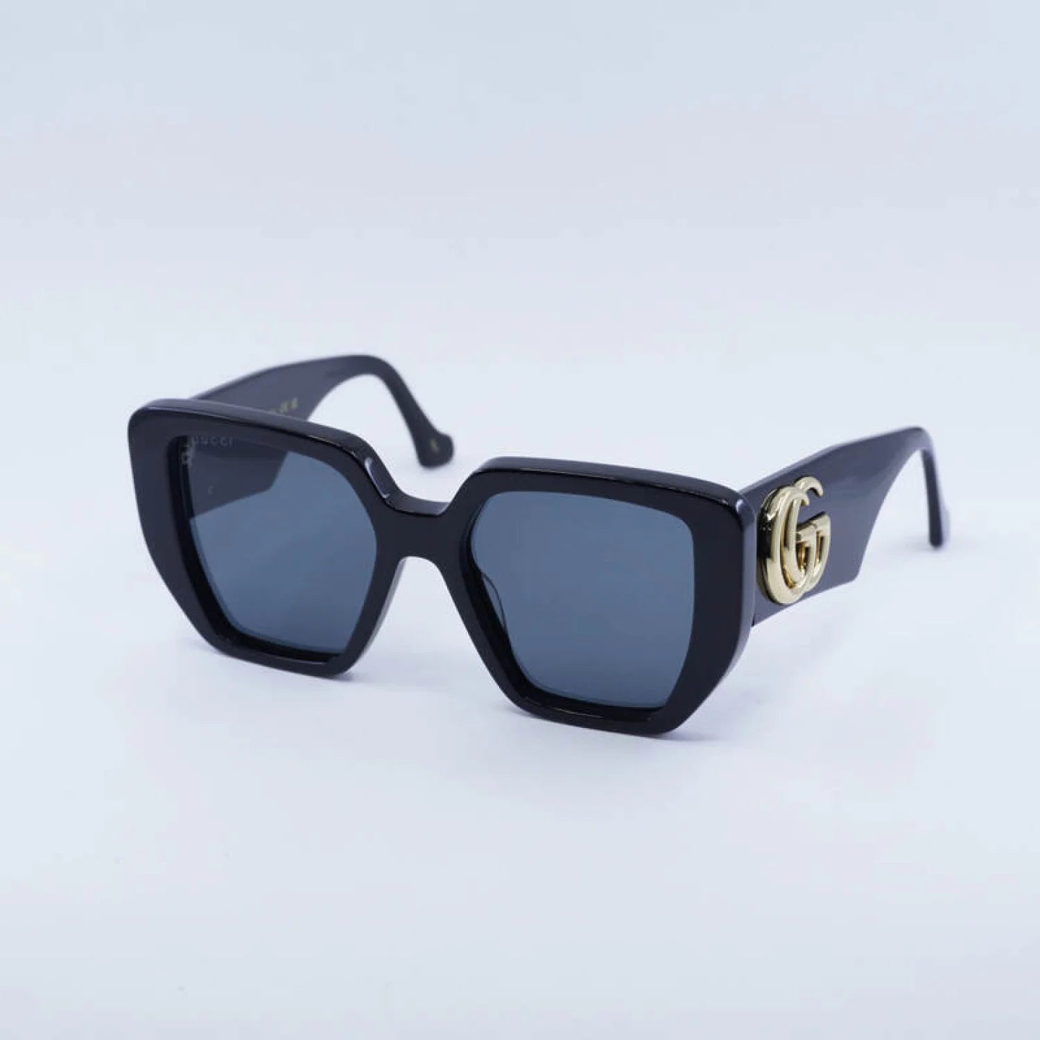 Black sunglasses with a gold logo on a light blue background